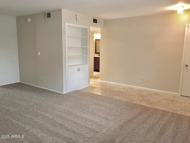 carpeted spare room with built in shelves