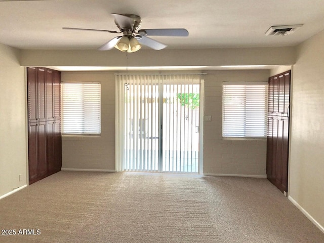 carpeted empty room with a wealth of natural light and ceiling fan