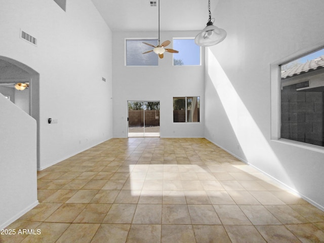 unfurnished living room featuring ceiling fan, light tile patterned floors, and a towering ceiling