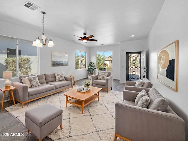 living room featuring visible vents and ceiling fan with notable chandelier