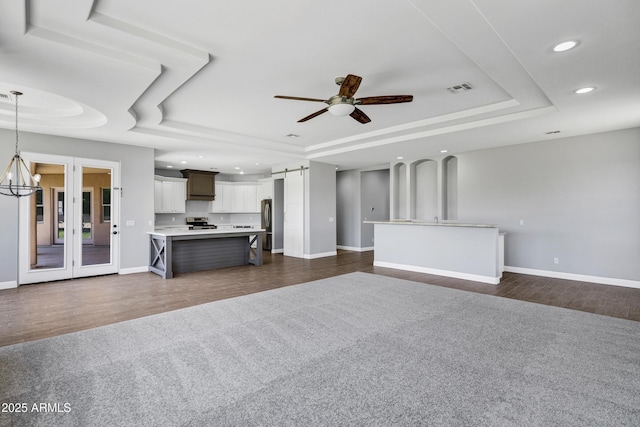 24615 S 182nd Pl, Gilbert, AZ 85298 - unfurnished living room with a tray ceiling, recessed lighting, ceiling fan, a barn door, and dark carpet