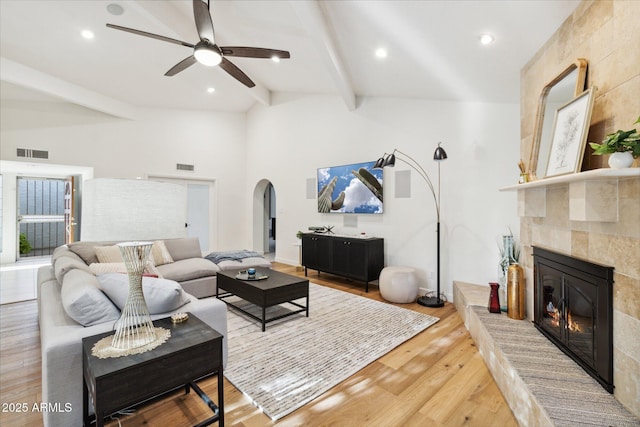 8405 E San Pedro Dr, Scottsdale, AZ 85258 - living room featuring a tiled fireplace, arched walkways, light wood finished floors, and a ceiling fan