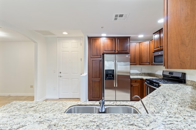 kitchen with light stone countertops, appliances with stainless steel finishes, and sink