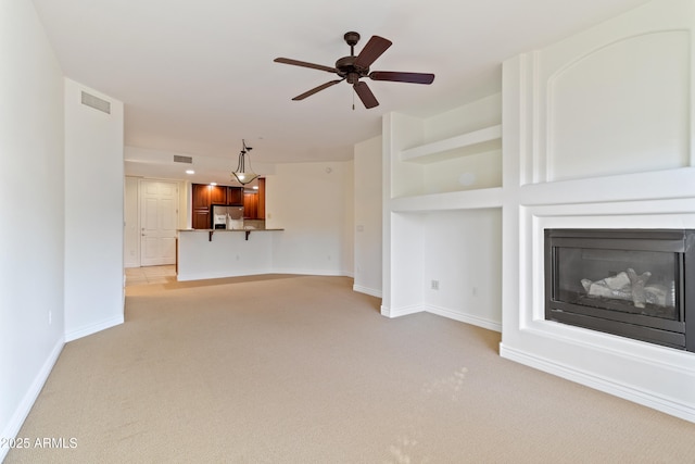 unfurnished living room with ceiling fan, built in features, and light carpet