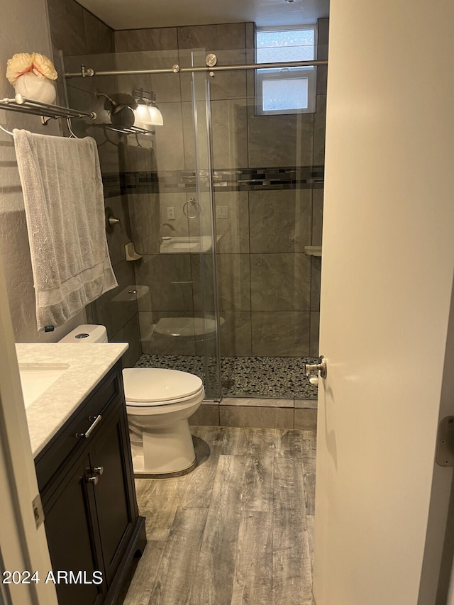 bathroom with an enclosed shower, toilet, wood-type flooring, and vanity