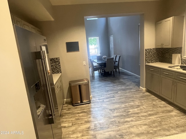 kitchen featuring gray cabinets, high end refrigerator, backsplash, light wood-type flooring, and sink