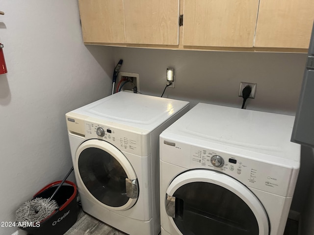 washroom featuring hardwood / wood-style floors, cabinets, hookup for an electric dryer, washer hookup, and washer and dryer