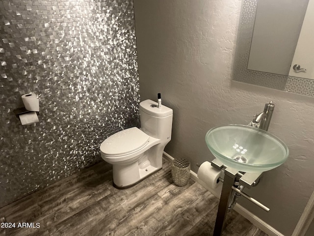 bathroom featuring toilet, hardwood / wood-style floors, and sink