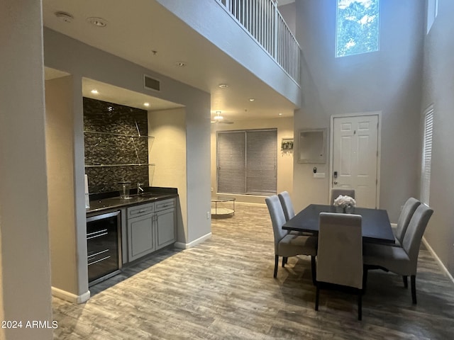 dining room featuring wine cooler, a high ceiling, dark hardwood / wood-style floors, and sink