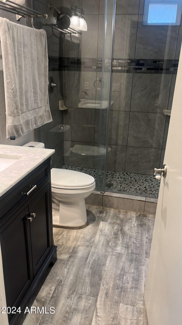 bathroom with walk in shower, toilet, wood-type flooring, and vanity