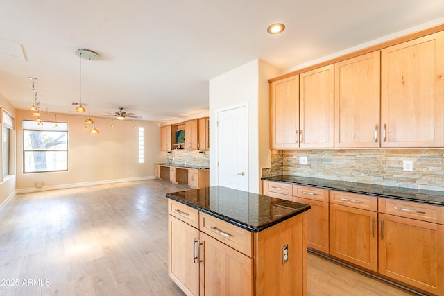 kitchen featuring a center island, pendant lighting, open floor plan, and dark stone counters