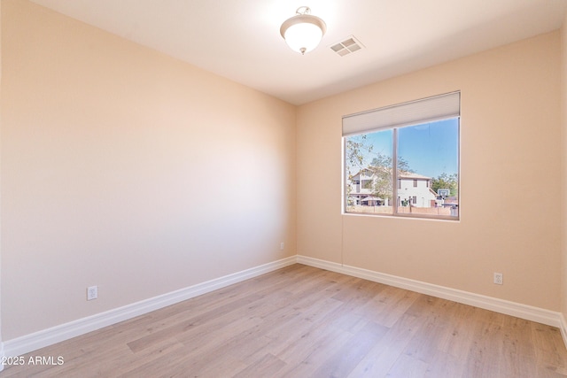 empty room featuring light wood finished floors, visible vents, and baseboards