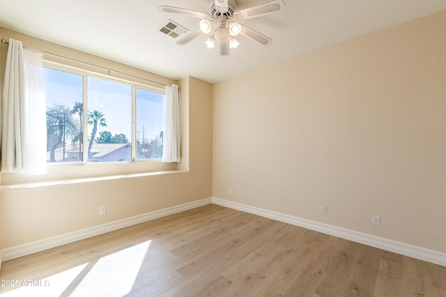 spare room featuring light wood-type flooring, visible vents, ceiling fan, and baseboards