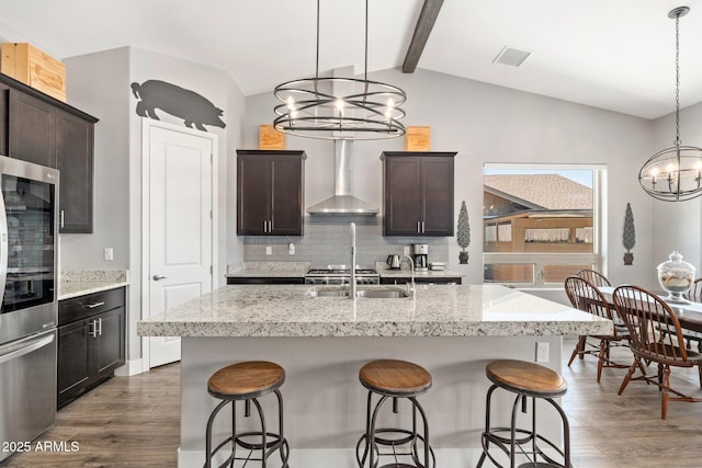 kitchen with wall chimney range hood, fridge, a notable chandelier, and dark wood-style floors