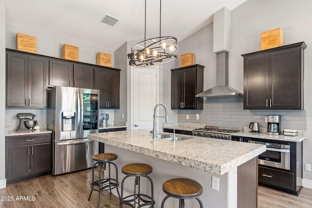 kitchen featuring a sink, stainless steel appliances, light wood-style floors, visible vents, and dark brown cabinets