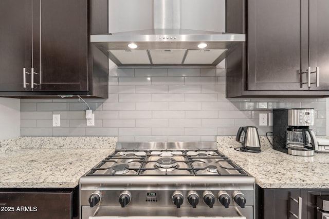 kitchen featuring ventilation hood, dark brown cabinets, backsplash, and gas stove