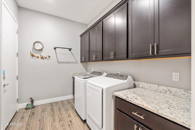 laundry room with baseboards, cabinet space, light wood finished floors, and washing machine and dryer