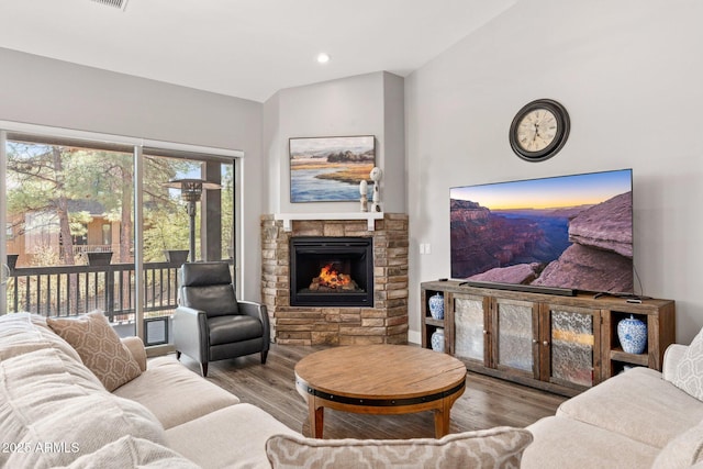 living area with visible vents, wood finished floors, and a stone fireplace