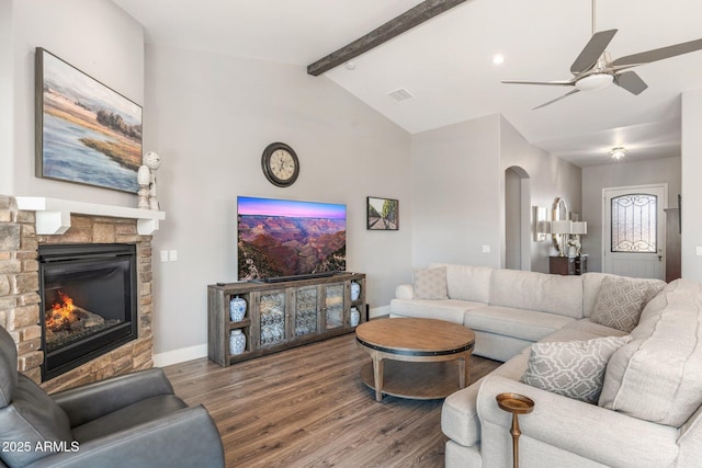 living room featuring visible vents, a fireplace, wood finished floors, a ceiling fan, and vaulted ceiling with beams