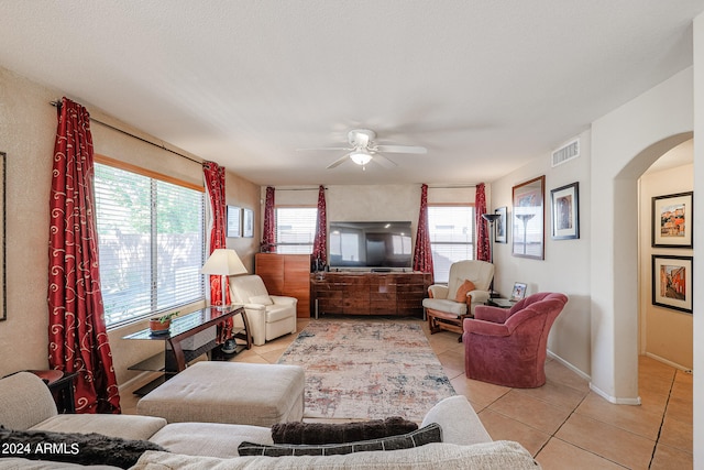 living room with a textured ceiling, plenty of natural light, light tile patterned floors, and ceiling fan