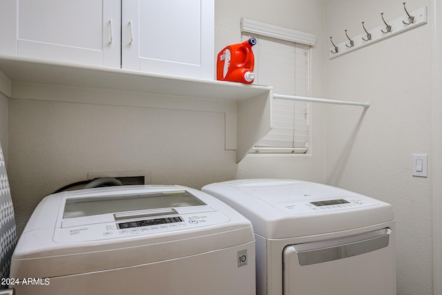 laundry room with washing machine and clothes dryer and cabinets