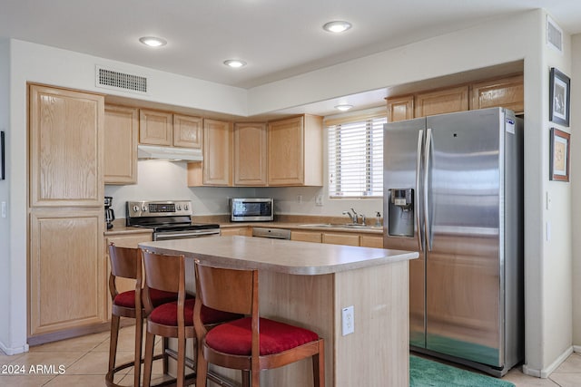 kitchen featuring light brown cabinetry, a center island, and stainless steel appliances