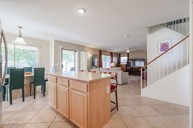 kitchen featuring pendant lighting, a wealth of natural light, a center island, and light brown cabinets