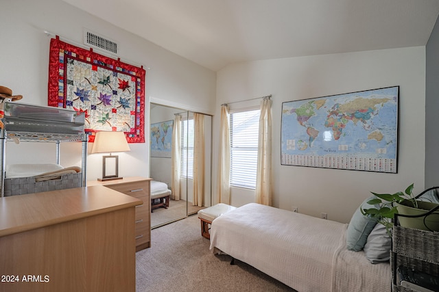 bedroom with lofted ceiling, light carpet, and a closet