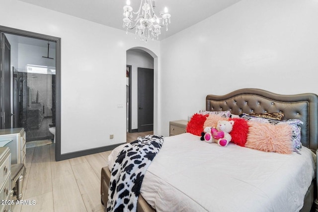 bedroom with a notable chandelier, light wood-type flooring, and ensuite bath