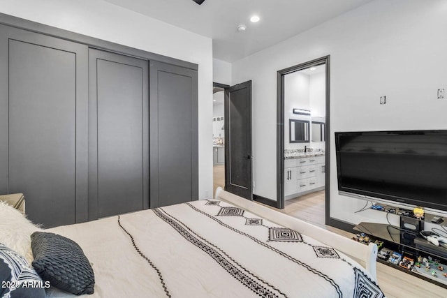 bedroom featuring light wood-type flooring, ensuite bathroom, and a closet