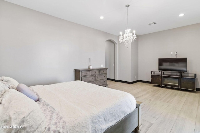 bedroom featuring light wood-type flooring and an inviting chandelier