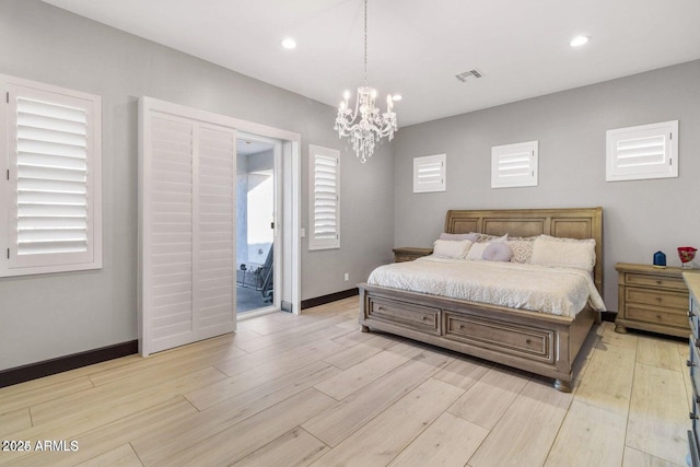 bedroom with a notable chandelier, light hardwood / wood-style floors, and connected bathroom