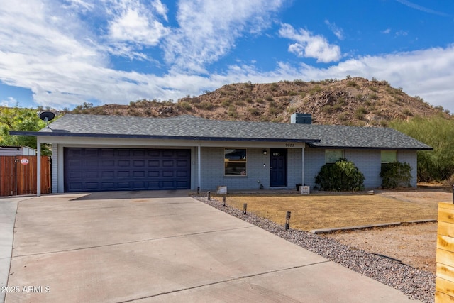 ranch-style house featuring a garage, driveway, brick siding, and fence