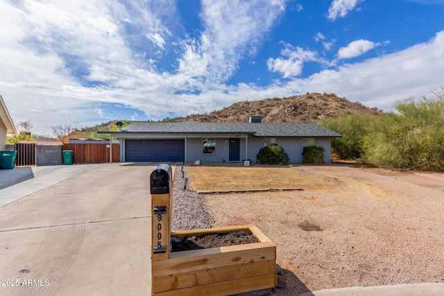 ranch-style house with a garage, driveway, fence, and a mountain view