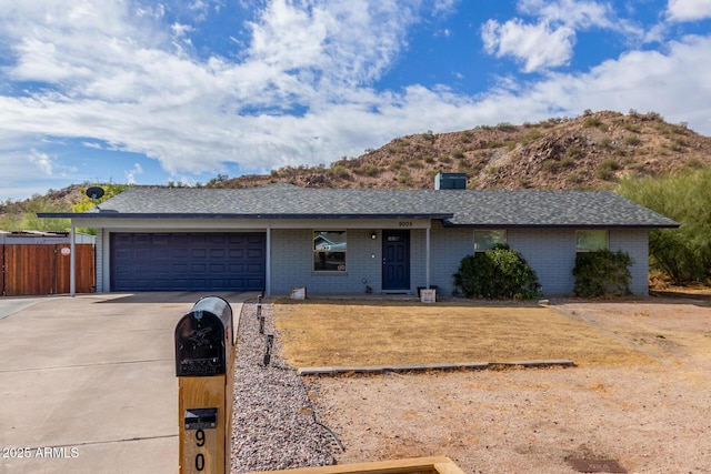 single story home featuring driveway, a garage, a chimney, a mountain view, and brick siding