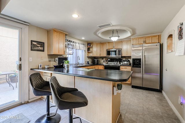 kitchen with hanging light fixtures, kitchen peninsula, appliances with stainless steel finishes, and a kitchen breakfast bar