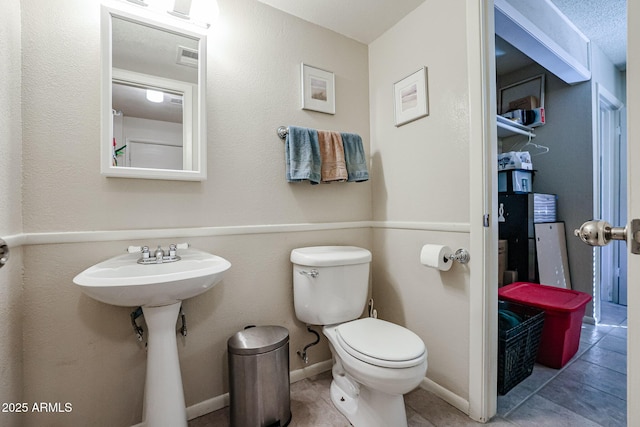 bathroom with toilet, tile patterned flooring, and a textured ceiling