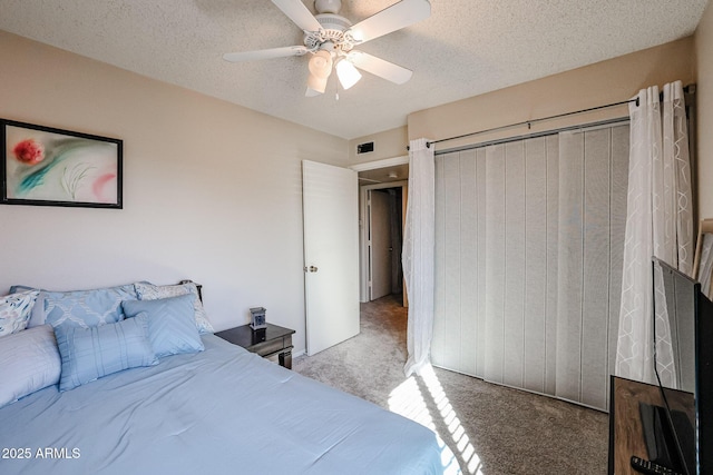 carpeted bedroom with ceiling fan, a textured ceiling, and a closet