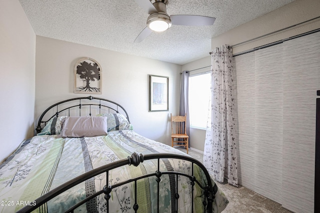 carpeted bedroom with ceiling fan and a textured ceiling