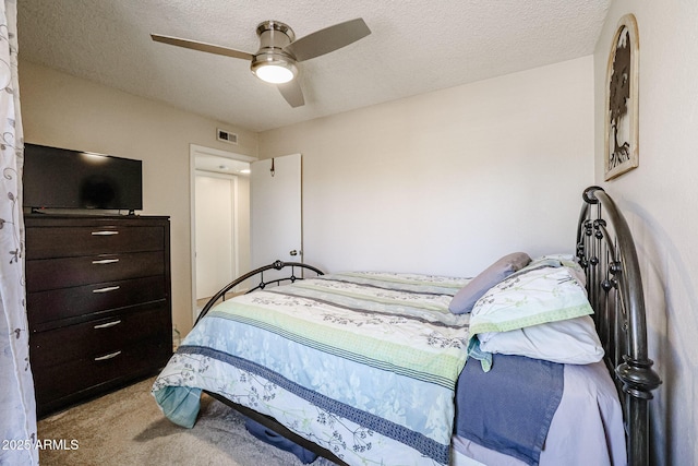 bedroom featuring ceiling fan, light colored carpet, and a textured ceiling