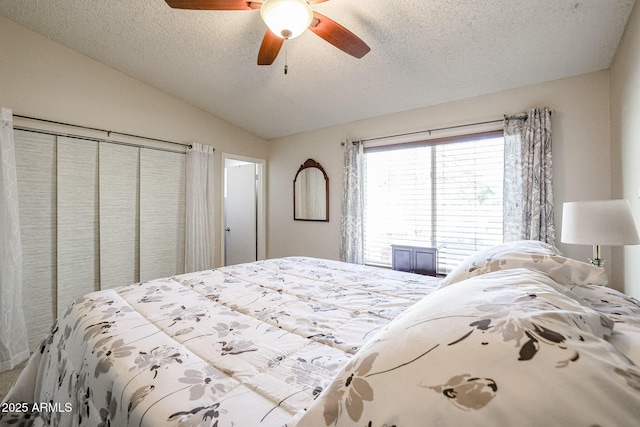 bedroom featuring ceiling fan, a textured ceiling, a closet, and lofted ceiling