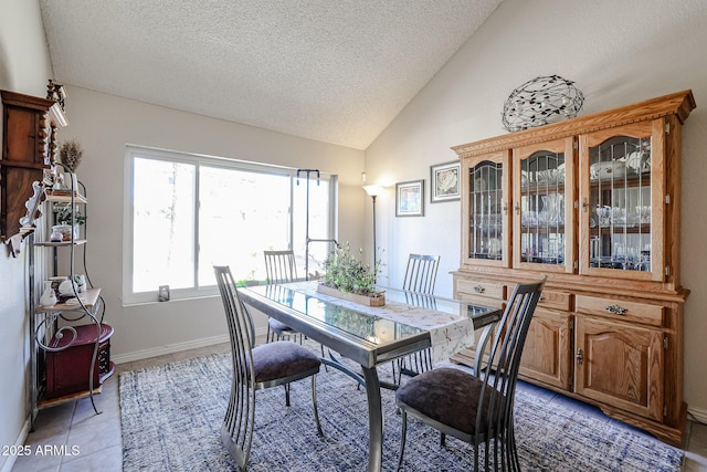 tiled dining area with vaulted ceiling and a textured ceiling