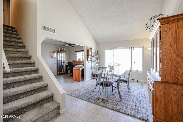 dining space featuring ceiling fan, light tile patterned floors, a textured ceiling, and lofted ceiling