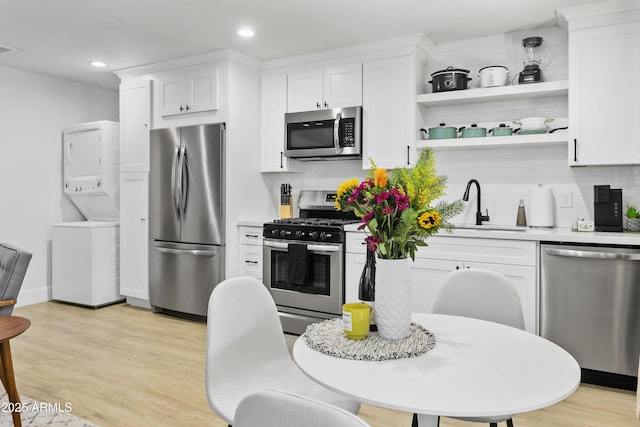 3139 N 40th St, Phoenix, AZ 85018 - kitchen featuring appliances with stainless steel finishes, stacked washer / drying machine, a sink, backsplash, and white cabinets
