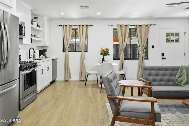 3139 N 40th St, Phoenix, AZ 85018 - kitchen with stainless steel appliances, a sink, light wood-style floors, white cabinets, and open shelves