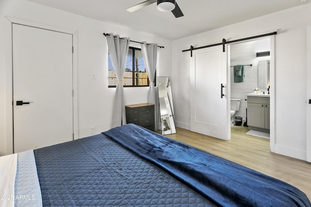 3139 N 40th St, Phoenix, AZ 85018 - bedroom featuring a barn door, light wood-style flooring, ensuite bath, and a ceiling fan