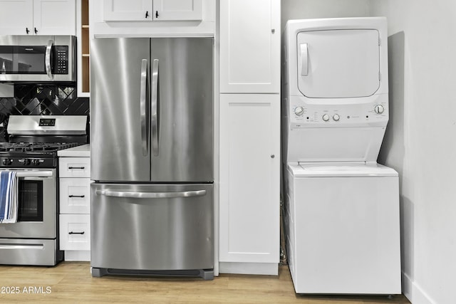 3139 N 40th St, Phoenix, AZ 85018 - kitchen featuring appliances with stainless steel finishes, stacked washer and clothes dryer, white cabinets, backsplash, and light wood finished floors