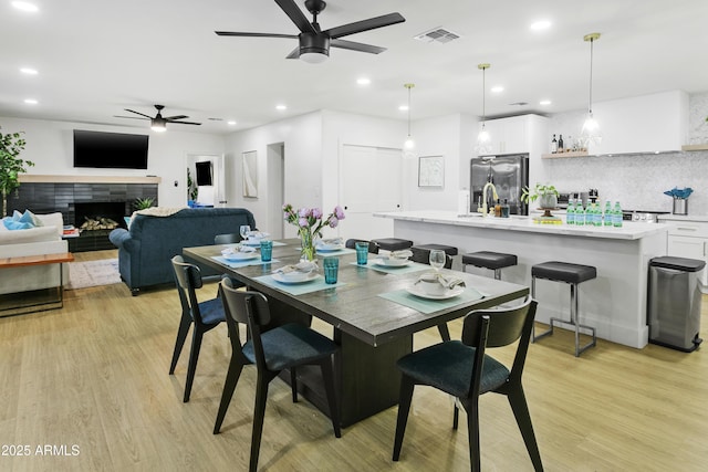 3139 N 40th St, Phoenix, AZ 85018 - dining space with ceiling fan, light wood-style floors, recessed lighting, and a tiled fireplace