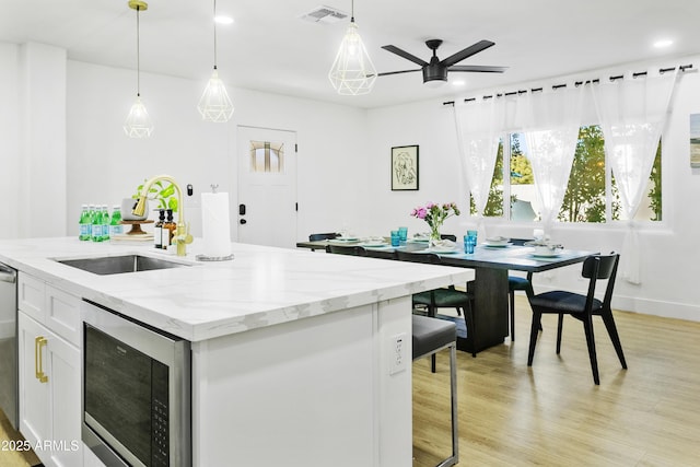 3139 N 40th St, Phoenix, AZ 85018 - kitchen with a sink, built in microwave, a ceiling fan, white cabinets, and light wood-style flooring