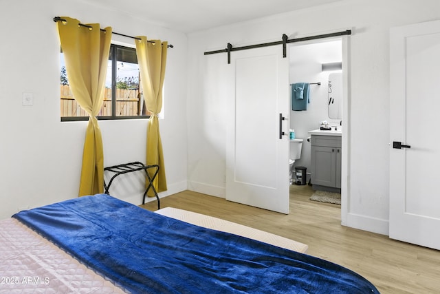 3139 N 40th St, Phoenix, AZ 85018 - bedroom with a barn door, wood finished floors, baseboards, and connected bathroom